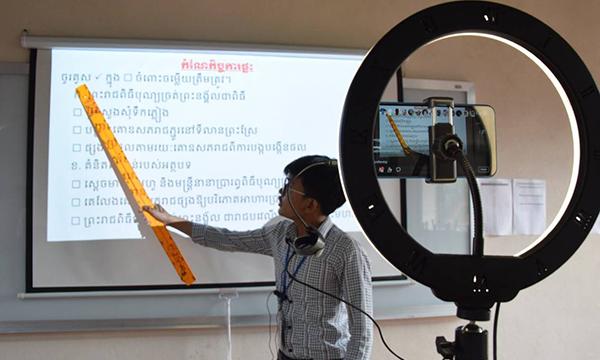 Ein Lehrer hält eine Unterrichtsstunde, die gefilmt und online übertragen wird