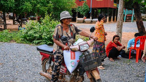 Une maman avec son sac de riz sur sa moto après une distribution de riz à Oudong