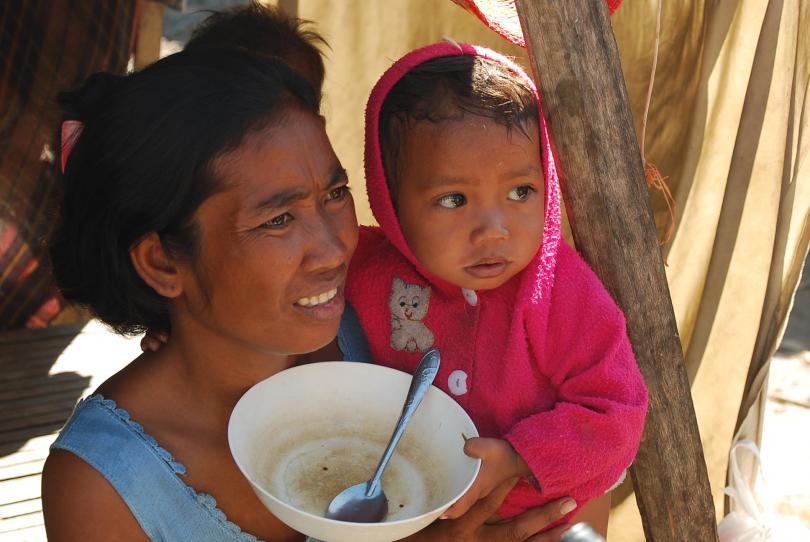 Une mère et son bébé avec un bol vide dans un quartier pauvre