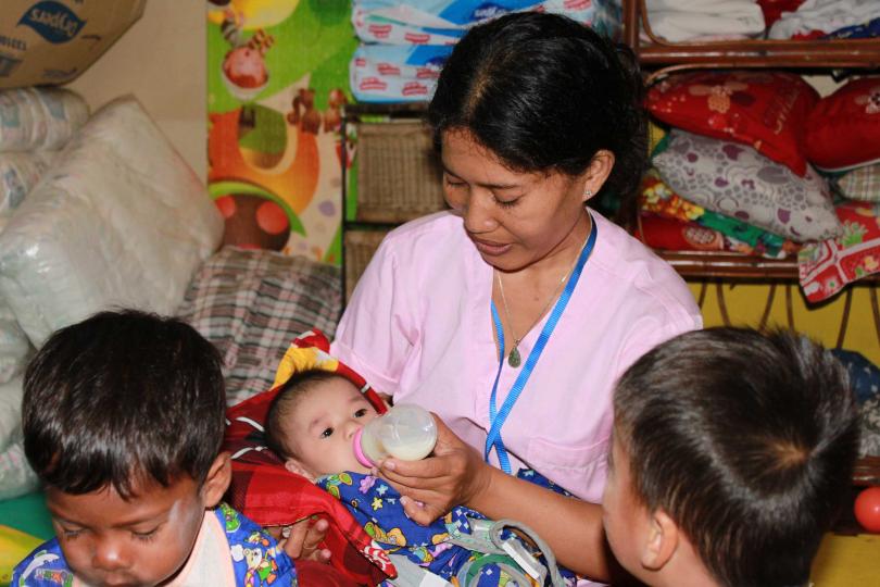 Phalla, l'une des responsables de la PMI de PSE, donne le biberon à un bébé