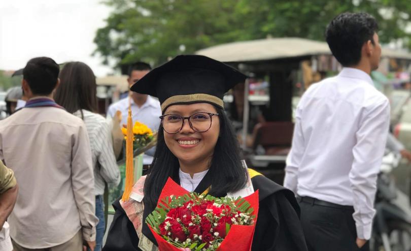 Sorya habillée pour sa remise de diplôme et avec un bouquet de fleurs dans les mains