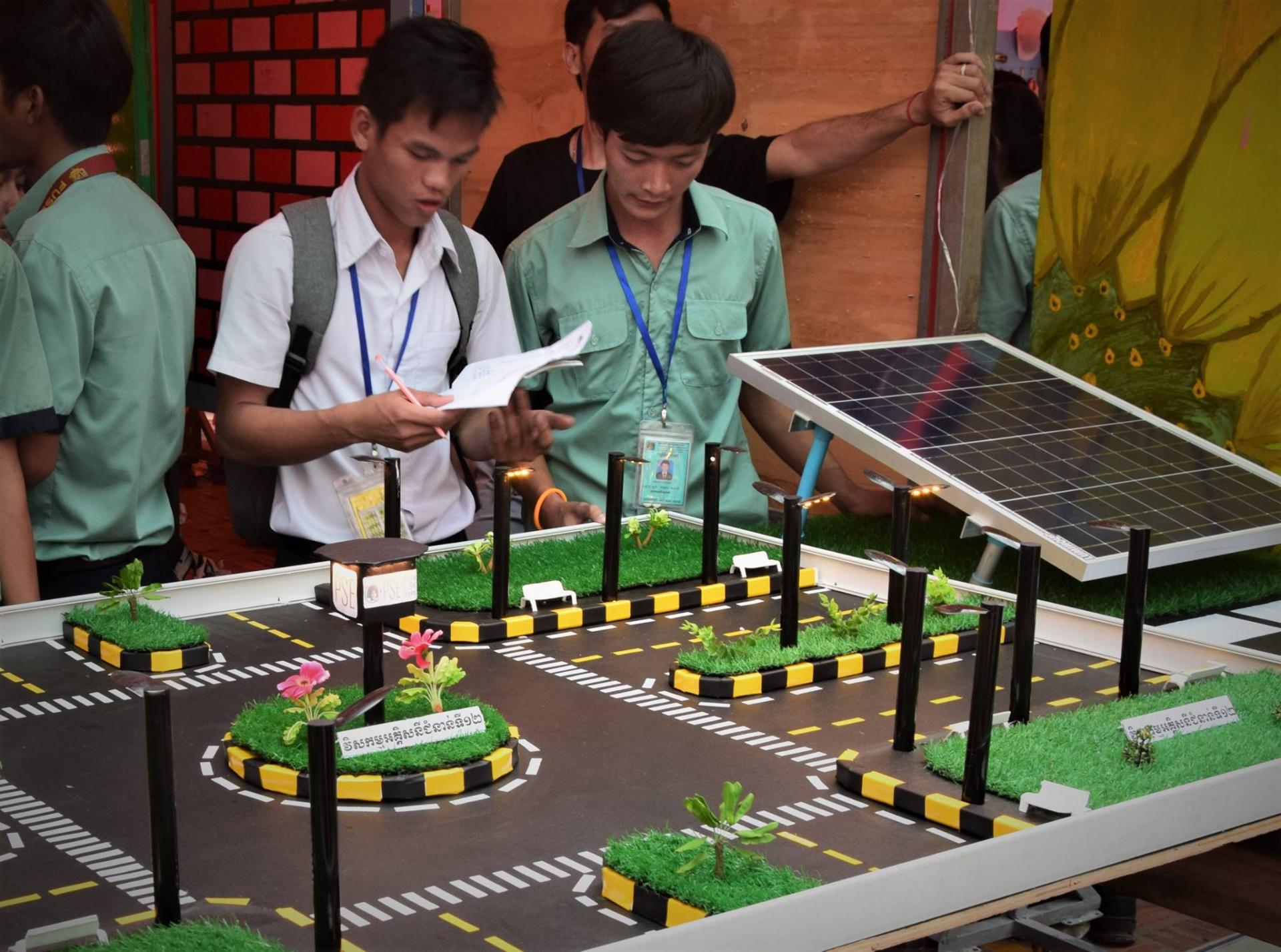Un élève s'intéresse à la maquette fonctionnant à l'électricité solaire de nos étudiants en électricité